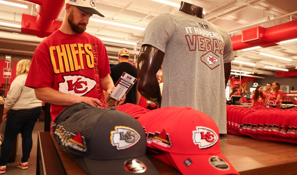 A man wearing a Chiefs t-shirt and hat looks at Chiefs merchandise in the Pro Shop.